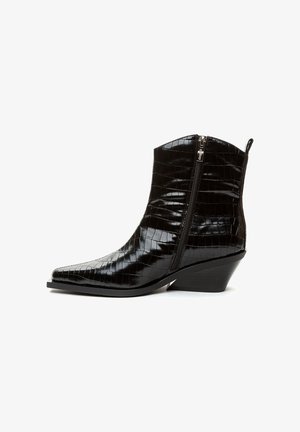 Juodas blizgus kulkšninis botas su krokodilo tekstūra, šoniniu užtrauktuku, smailiu pirštu ir madingu vidutinio aukščio kulnu.