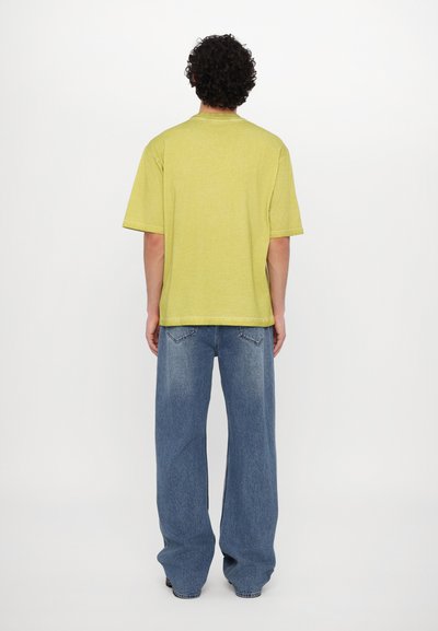 Short-sleeve, lime green t-shirt with a crew neckline, paired with light blue wide-leg jeans featuring back pockets and a textured finish.