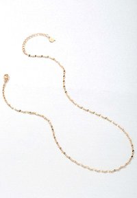 Collar de cadena de color dorado con eslabones retorcidos y cierre de gancho, que presenta una textura suave y un diseño uniforme.