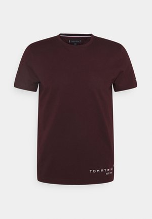 Camiseta de manga corta color burdeos oscuro con cuello redondo y pequeño logo "Tommy Hilfiger EST. 1985" cerca del dobladillo inferior sobre fondo blanco.