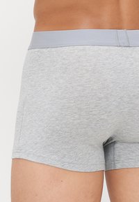 Boxers en coton gris avec une taille douce et élastique. Le tissu présente une texture lisse avec des détails de couture minimaux.