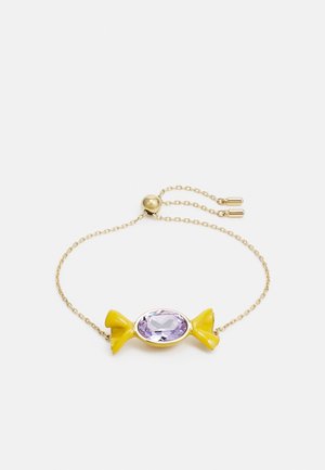 Gouden kettingarmband met verstelbare sluiting, voorzien van een geel snoepvormig bedeltje en een centrale ovale paarse edelsteen.