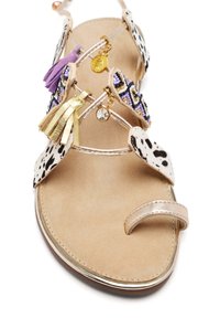 Sandalo con cinturini, dal design a macchie beige e nere, decorato con pompon colorati e perline, presenta un bordo metallico e una suola piatta.
