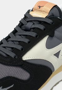 Black and gray sneaker featuring a mix of suede and mesh material, with gray laces, a cream accent, and a light brown tongue with branding.