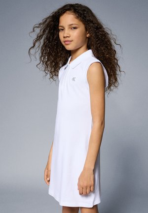 Weißes ärmelloses Polokleid mit Kragen, das ein kleines gesticktes Logo auf der Brust hat. Glatte Baumwolltextur, gerade Saumlinie.