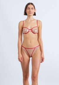 Διαφανές σετ εσωρούχων με κόκκινες λεπτομέρειες, περιλαμβάνει στηθόδεσμο με μπανέλες και ρυθμιζόμενους ιμάντες, σε συνδυασμό με αντίστοιχο διάφανο στρινγκ.