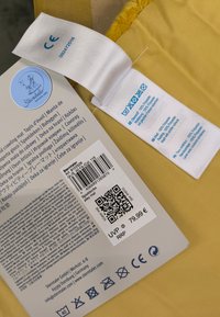 Yellow play mat with soft, textured surface, rectangular shape, and stitched edges. Includes care label and product information on packaging.