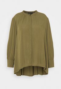 Blouse à manches longues, couleur vert olive, avec un col haut, fermeture par boutons à l'avant, détails plissés et un dos légèrement courbé et plus long.