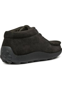 Stivali alla caviglia in suede nero con punta rotonda, superficie testurizzata e suola in gomma flessibile con motivi a cerchio.