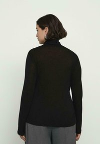 Czarny longsleeve z kołnierzem typu golf, wykonany z miękkiego, lekkiego materiału, charakteryzujący się dopasowanym krojem i gładką fakturą.