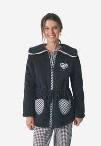 Accappatoio in pile blu notte con un ampio colletto, toppe a forma di cuore e dettagli in vichy sulle tasche. Presenta una vita con laccio e una texture morbida.