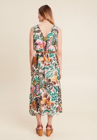 Blumenkleid in Midi-Länge mit V-Ausschnitt, versehen mit einer Mischung aus rosa, grünen und braunen Blättern. Der Stoff ist leicht und das Kleid hat eine taillierte Taille mit Gürtel.