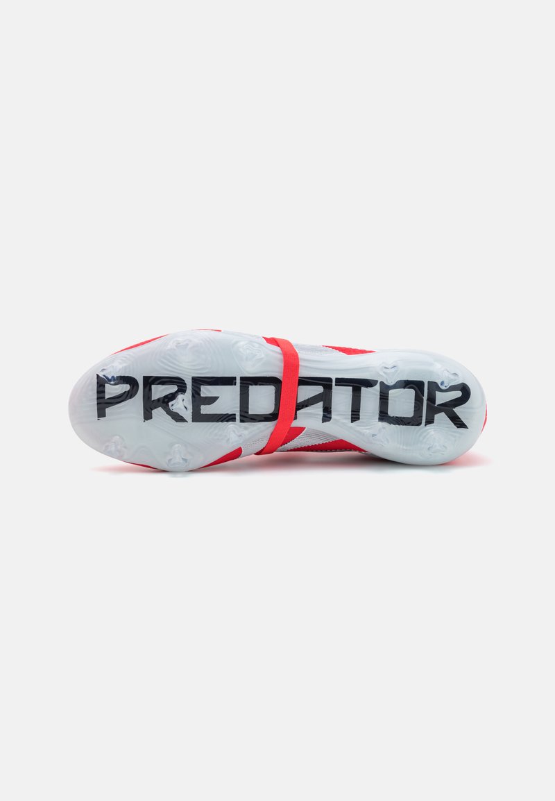 Roter Sportschuh mit strukturiertem Obermaterial, verstellbarem Riemen und einer klaren Laufsohle, auf der in fetten schwarzen Buchstaben "PREDATOR" gedruckt ist.