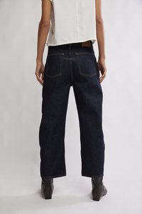 Jean en denim foncé taille haute avec une coupe décontractée, doté de surpiqûres jaunes contrastantes, cinq poches, et un tissu texturé.