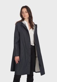 Granatowy wodoodporny płaszcz przeciwdeszczowy z kapturem, zapinany na guziki, z kieszeniami. Posiada gładką teksturę i kontrastowe jasne wykończenie wnętrza.