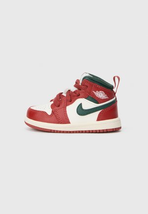 Červené a biele vysoké tenisky s zelenými akcentmi, textúrovaná koža, ploché šnúrky a malé logo na päte. Krémová gumová podrážka.