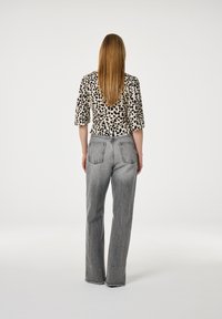 Tijgerprint blouse met opbollende mouwen, gecombineerd met hoogstaande grijze jeans met een rechte pasvorm en een rafelige zoom.