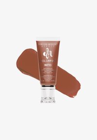 Tubo de pigmento líquido mate Colorfix de Danessa Myricks Beauty en marrón cálido con una muestra detrás sobre un fondo blanco.