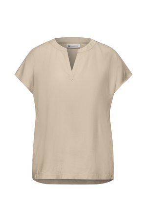 Blouse beige à manches courtes avec un col rond fendu et des détails subtils de coutures, portant l'étiquette "Street One" à l'intérieur du col.