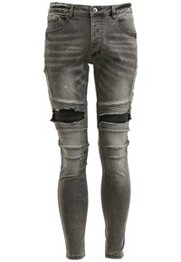 Vaqueros pitillo de mezclilla gris con rodillas rasgadas, detalles desgastados y salpicaduras de pintura. Cuentan con bolsillos estándar y trabillas para cinturón.