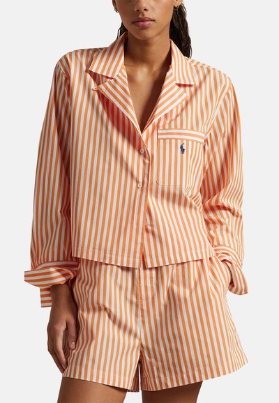 Dwuczęściowa piżama w pomarańczowo-białe paski, składająca się z koszuli na guziki z kieszenią oraz pasujących szortów, wykonana z lekkiej bawełnianej tkaniny.