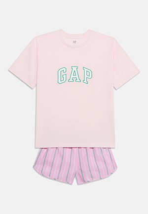 Vaaleanpunainen lyhythihainen T-paita, jossa vihreä "GAP"-teksti, yhdistetty vaaleanpunaisiin ja valkoisiin raidallisiin shortseihin, yksivärisellä taustalla.