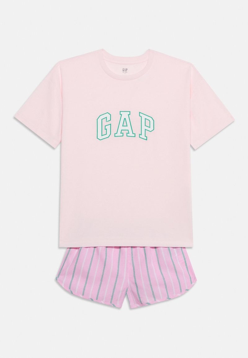 Φωτεινό ροζ κοντομάνικο μπλουζάκι με πράσινα γράμματα "GAP" συνδυασμένο με ροζ και λευκό ριγέ σορτς, τοποθετημένο σε μονόχρωμο φόντο.
