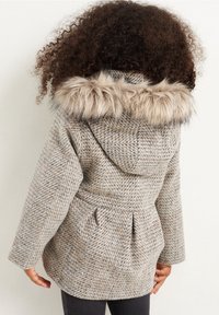 Ljust grå kappa med ett mönstrat väv, med en huva som har fälls av fuskpäls, cinchade midja med knytband och sidofickor. Texturerad finish.