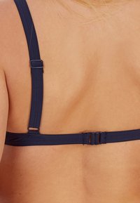 Dunkelblauer BH mit breiten Trägern, verstellbaren Haken und glatter Textur. Verfügt über einen Standardverschluss hinten für sicheren Halt.