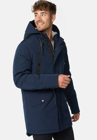 Mørkeblå isoleret parka med hætte, med sorte akcenter, lynlåslukning, dobbelte forlommer og snoretræk på hætten.