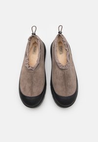 Brown suede slip-on shoes with a textured black rubber sole, elasticized upper rim, and fleece lining for comfort. Top view.