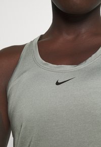 Canottiera Nike verde chiaro realizzata in tessuto morbido e elastico. Presenta un collo a gomito e un logo Nike nero vicino al centro.