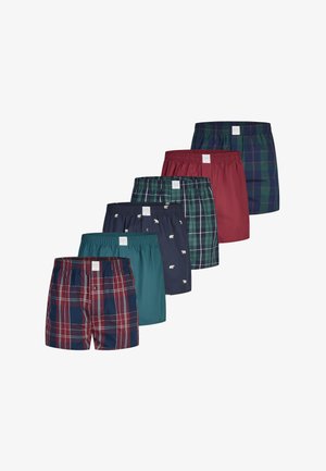 Zes paar herenboxershorts in verschillende kleuren en patronen, waaronder ruitpatroon, effen teal, effen bordeauxrood en marineblauw met kleine witte beren.