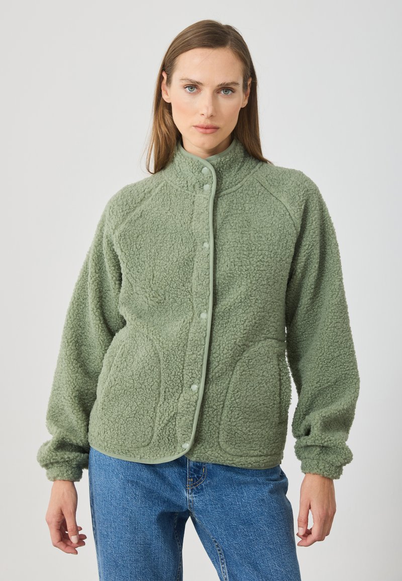 Fleece bunda v světle zelené barvě, s vysokým límcem, zapínáním na cvoky, raglánovými rukávy a dvěma předními kapsami s texturovanou tkaninou.