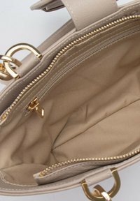 Borsa a mano beige con un esterno testurizzato, hardware dorato e una tasca interna con zip. La fodera è in un tessuto leggero e liscio.