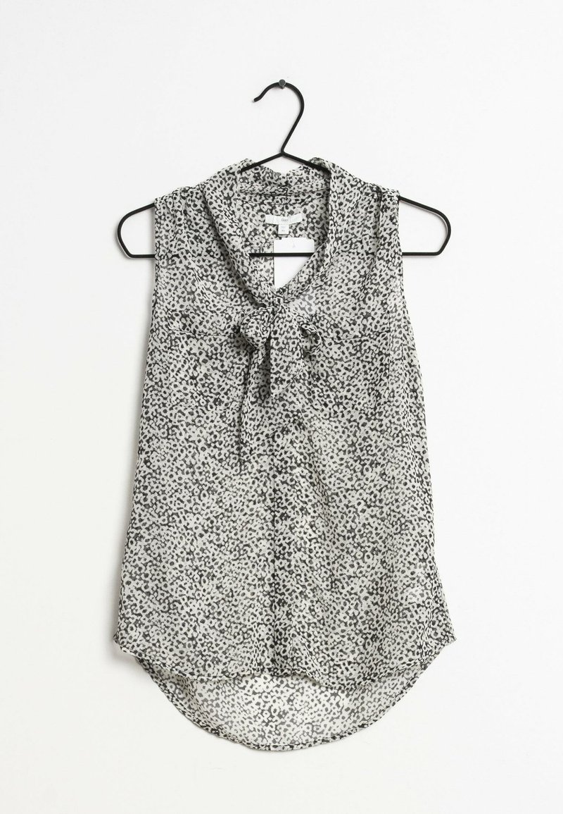 Blouse sans manches avec imprimé léopard noir et blanc, détail à nouer au col, suspendue sur un cintre noir sur fond blanc.