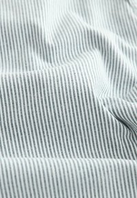 Svetlomodrá tkanina s úzkymi bielymi pruhmi, ktorá má hladkú, mäkkú textúru a jemný lesk, ideálna na oblečenie alebo textil do domácnosti.