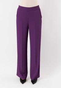 Pantaloni larghi viola realizzati in tessuto leggero, con vita elastica e superficie liscia, abbinati a scarpe nere con punta affusolata.