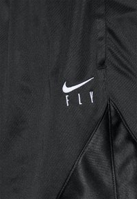 Zwarte sportshorts gemaakt van een gestructureerde stof. Bevat een wit Nike-logo en de tekst "FLY" gedrukt op de zijkant, met een zijsplit voor extra flexibiliteit.