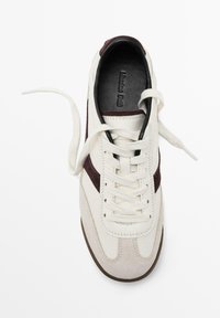 Sneakers bianchi in suede con accenti bordeaux e lacci bianchi. Presentano una punta rotonda e una suola in gomma texturizzata. All'interno, fodera nera visibile.