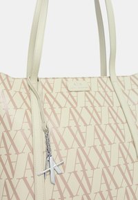 Borsa tote beige con motivo logo, finitura testurizzata, doppi manici e accessori in argento. Presenta un'etichetta con logo attaccata con una catena.