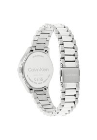 Reloj de pulsera de acero inoxidable con acabado pulido, que presenta una pulsera plateada y una caja redonda. Logo de la marca grabado en la parte posterior.