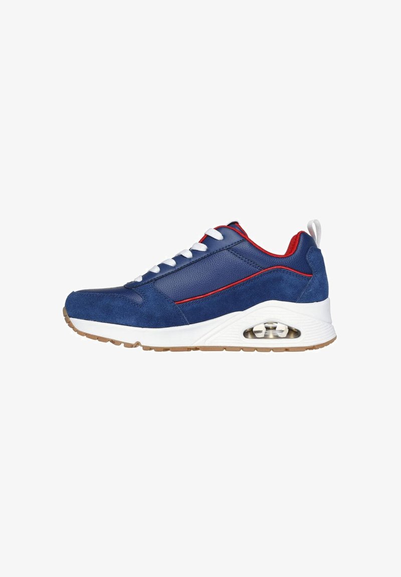 Zapatilla de deporte azul marino con materiales de ante y cuero, entresuela blanca, acentos rojos y amortiguación de aire en el talón. Suela de goma.