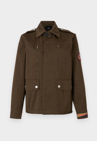 Καφέ στρατιωτικό μπουφάν με κουμπωτές τσέπες με καπάκι, τσέπες στο στήθος με φερμουάρ, επιβραχιόνια στους ώμους και κεντητό έμβλημα στη μανσέτα και το μανίκι του αριστερού χεριού.