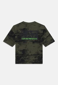 Oliven grønn t-skjorte med korte ermer og et teksturert svart grafisk design. Har en fremtredende svart "EA7"-logo med "EMPORIO ARMANI" i grønt under.