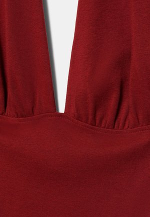 Dieprode gebreide stof met een gerimpelde naadtoevoeging die een V-vormige halslijn vormt op een kledingstuk.