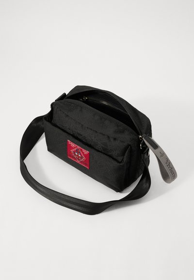 Schwarze Stoff-Crossbody-Tasche mit strukturiertem Finish, ausgestattet mit einem roten Logo-Patch und zwei Reißverschlussfächern. Verstellbarer schwarzer Gurt.
