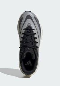 Czarno-szare buty sportowe o smukłym designie, z teksturowaną cholewką, okrągłym noskiem i kontrastującą białą podeszwą. Czarna wstążka i akcenty.