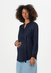Blusa da maternità blu navy con colletto alla cinese, chiusura con bottoni, dettaglio elastico smock e vita con fiocco, realizzata in tessuto leggero.