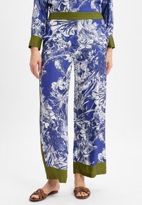 Musterhosen in Blau und Weiß mit floralen Designs und olivgrünen Akzenten; weit geschnitten; glattes, leichtes Material; elastischer Bund.